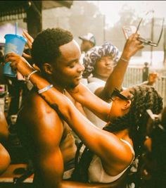 a group of people standing around each other with one person holding up a cup in the air