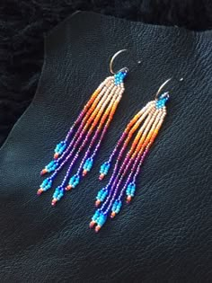 two pairs of beaded earrings sitting on top of a black surface