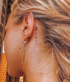 a woman with ear piercings on her left side behind her ear is looking down at the ground