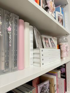 a book shelf filled with lots of books and binders on top of white shelves