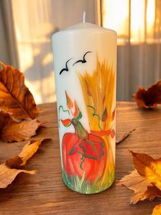 a lit candle sitting on top of a wooden table covered in leaves and pumpkins