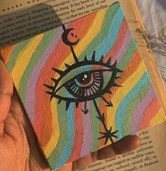 someone is holding up a book with an eye painted on it