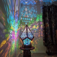 a lamp sitting on top of a table in front of a wall covered with stained glass