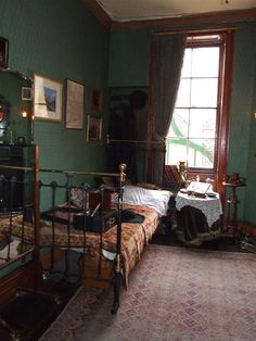 an old fashioned bedroom with green walls and antique furniture, including a wrought iron bed frame