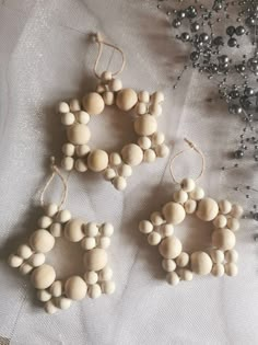 three wooden beads are hanging from strings on a white fabric surface with silver and black ornaments