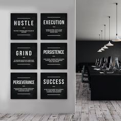 four black and white posters hanging on the wall in a conference room with wooden flooring