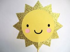 a yellow paper sun on a stick with pink cheeks and black eyes is shown in front of a white background