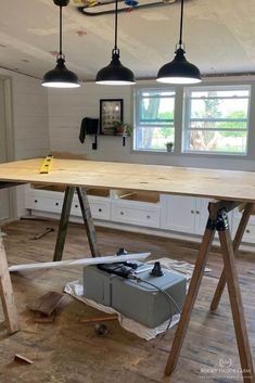 a workbench in the middle of a room under construction with three lights hanging over it