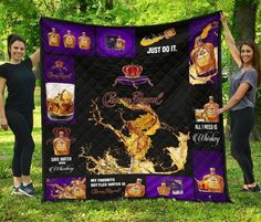 two women are holding up a quilt that is covered in gold and purple liquor bottles