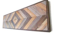 a wooden wall hanging on the side of a white wall with an arrow shaped design