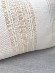 a close up view of a white and beige striped pillow on a gray bed sheet