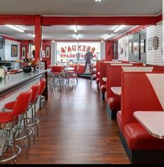 the inside of a fast food restaurant with red and white booths, bar stools, and tables