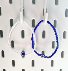 two bracelets with blue beads are hanging on a wall