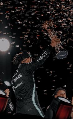 a man holding up a trophy while surrounded by confetti