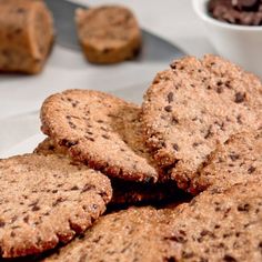 chocolate chip cookies on a plate next to a bowl of chocolate chips and a spoon