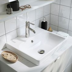 a bathroom sink sitting on top of a white counter next to a shelf filled with items