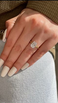 a woman's hand with white manies and a diamond ring on her finger