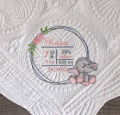 the birth quilt has an elephant on it and is embroidered with pink flowers in a circle