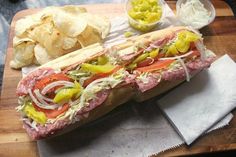 a sub sandwich on a cutting board with potato chips