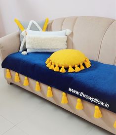 a blue couch with yellow tassels and a white pillow on it's back