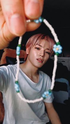 a person holding up a beaded necklace in front of their face