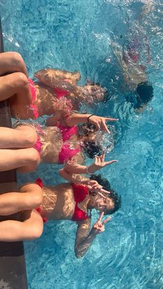 several people in the pool with their hands on the edge of the pool and one person wearing a red swim suit