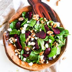 a salad with beets, feta cheese and walnuts in a wooden bowl