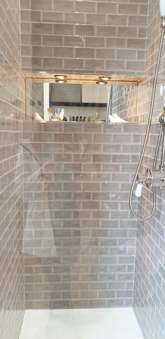 a bathroom with a walk in shower next to a tiled wall