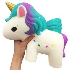 a hand holding a white and purple unicorn toy