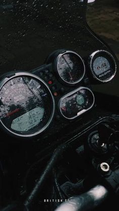 the gauges and dash lights of a motorcycle are covered in raindrops as it rains