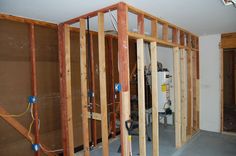 an unfinished room with wood framing and electrical wires in the wall next to the water heater