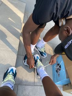 two people tying their tennis shoes on the sidewalk