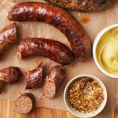 sausages, mustard and other condiments are on a cutting board next to some meat