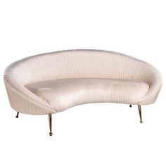 a curved white couch sitting on top of a metal stand