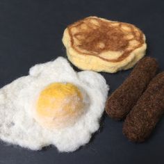 an egg, sausages and some type of food on a black tablecloth surface