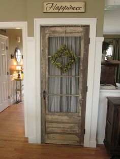 an old door on a kitchen pantry is decorated with a wreath for the front door