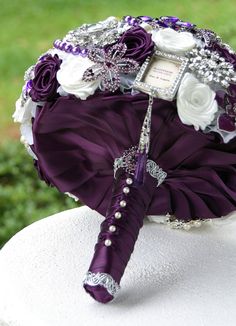 the bridal bouquet is made up of purple and white flowers, with silver accents