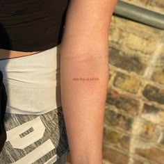 a woman with a tattoo on her arm that says one day at a time,