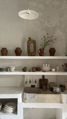 the shelves are full of dishes and vases on top of each other in this room