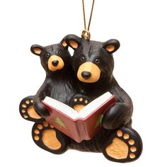 two black bears are reading a book ornament on a white background and hanging from a gold chain