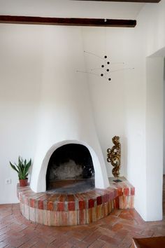 a living room with a brick fireplace next to a potted plant on the floor