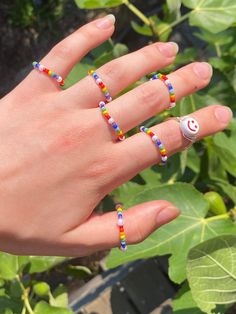 a woman's hand with colorful beaded rings on it and a smiley face ring