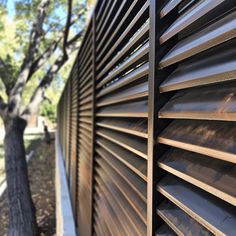 the side of a metal fence that is made out of wood and has slats on it