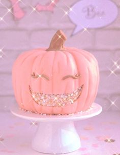 a pink pumpkin with a smile on it's face sitting on a cake plate