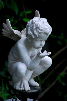 a statue of a cupid holding cherubs with red hearts in its hands