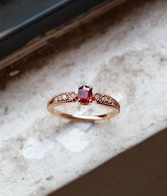 a close up of a ring with a red stone in the middle and white stones around it