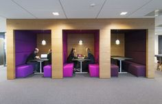 two people sitting at a table in a room with purple booths and lights on the walls