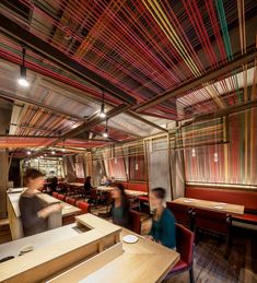 people sitting at tables in a restaurant with colorful lines on the walls and ceiling above them