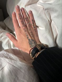 a woman's hand with tattoos on it and writing on the wrist is laying in bed