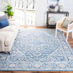 a living room with a blue rug on the floor and white furniture in front of it